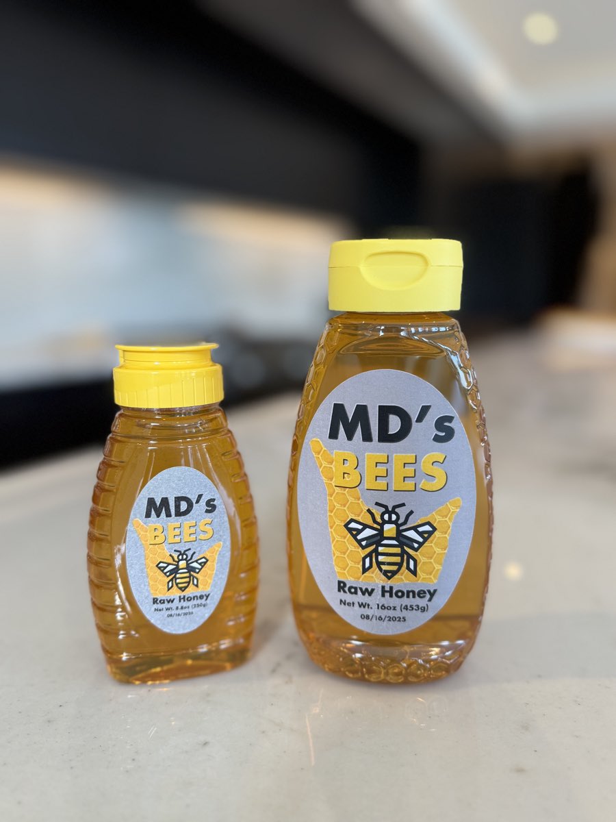 The 8.8 oz and 16 oz bottles of MD's Bees raw honey side by side